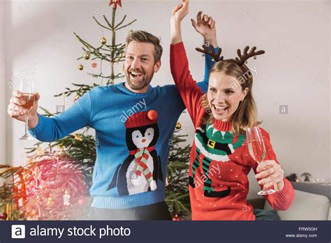 For children it often means presents, presents and more presents! Two people with ugly Christmas sweaters dancing in front ...