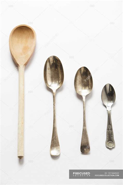 Closeup Top View Of Wooden Spoon And Different Sized Metal Spoons