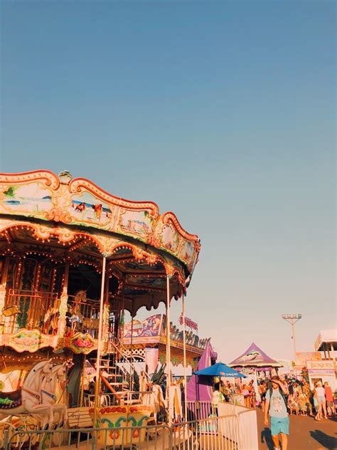 People Are Walking Around An Amusement Park With Carousels And Rides On