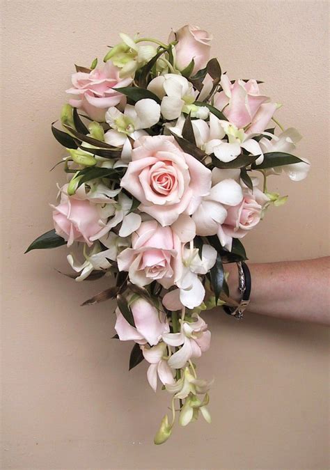 A Bridal Bouquet With Pink Roses And White Orchids Is Held By A Womans