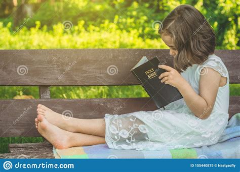reading the holy bible in outdoors christian girl holds bible in her hands sitting on a bench