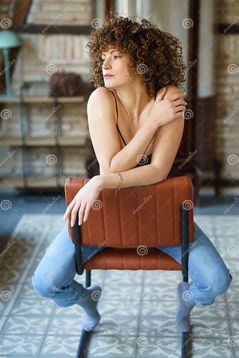 Woman In Underwear Sitting On Chair Against Brick Wall Stock Image