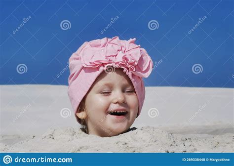 A Small Child Plays In The Sand On The Beach Buried Up To His Head A