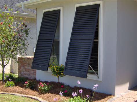 Storm shutter warehouse specializes in customizing storm and hurricane protection for nearly any window or entrance of your building or home. Close-up view of a pair of black bahama-style hurricane ...