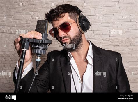 Singer With Sunglasses In Front Of A Microphone Holding Him By Hand And