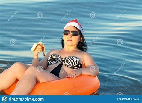 A Brunette Woman In A Swimsuit And A Santa Claus Hat Celebrates
