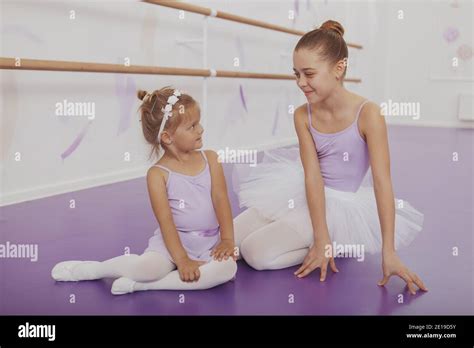 Two Lovely Young Ballerinas Smiling At Each Other Resting On The Floor