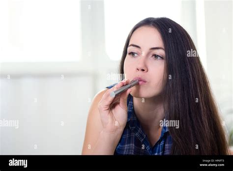 Portrait Of Women Smoking An Electronic Cigarette Lying On Bed At Home
