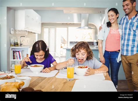 Los Niños Desayunar Mientras Los Padres Están De Pie En La Tabla Fotografía De Stock Alamy