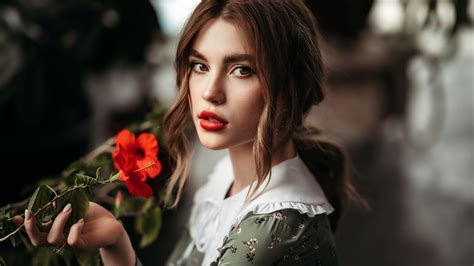 Beautiful Girl Model With Red Hibiscus Flower In Hand Standing In Blur