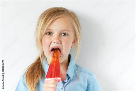 Portrait Of Caucasian Child Licking Popsicle And Looking At The Camera