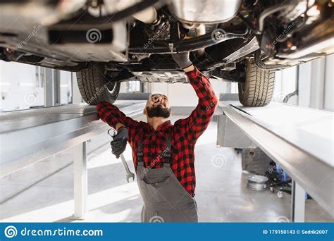 Auto Mechanic Working Underneath A Lifted Car Auto Mechanic Working In