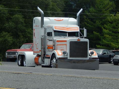 An Orange And White Semi Truck Parked On The Side Of The Road