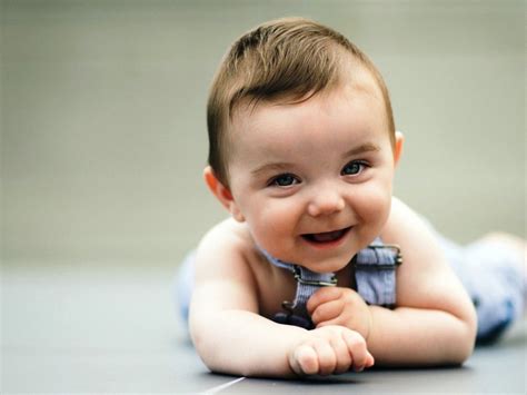 Cute Smiley Baby Is Lying Down On Floor Wearing Light Blue Dress In A