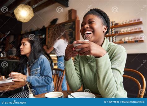 Young Woman Laughing Over Coffee With Friends In A Cafe Stock Photo