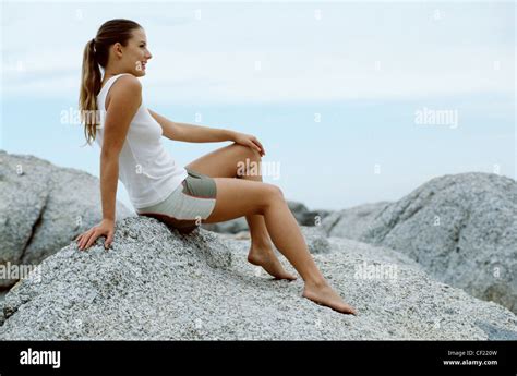 Lächelnd Barfuß Brünett Weiblich Pferdeschwanz Haare Sitzen Auf Einem Felsen Am Strand Mit