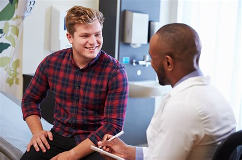 Male Patient And Doctor Have Consultation In Hospital Room Stock Photo