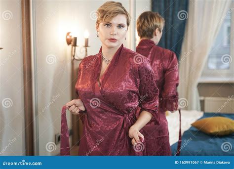 stylish pin up short hair blonde woman with plus size curvy body posing in fashion red bathrobe