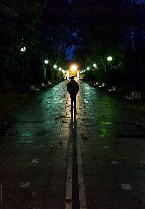 Man Walking Alone Throug A Dark Street At Night Del Colaborador De