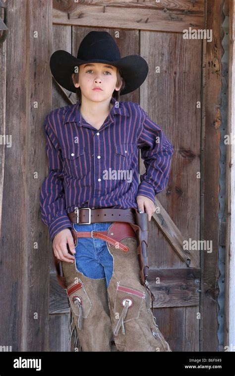 A Young Cowboy Standing In Front Of An Old West Town Stock