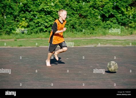Barefoot Boy Playing Football Stock Photo Alamy