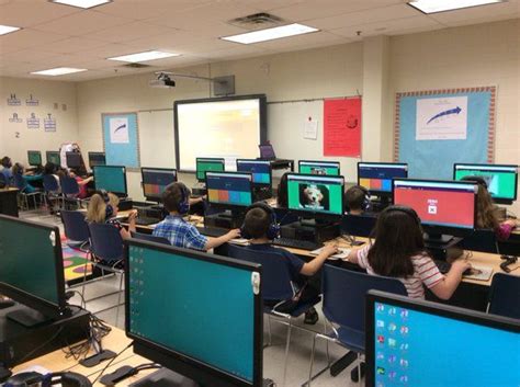 A Classroom Full Of Students Sitting At Desks With Computers