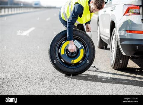 Man Changing Wheel Standing With Spare Wheel Near The Broken Car On The Roadside Stock Photo Alamy
