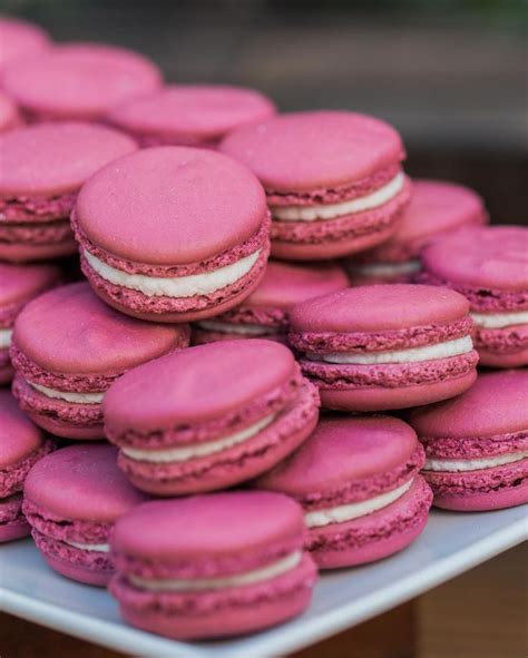 A Pile Of Pink Macaroons Sitting On Top Of A White Plate Next To Each Other