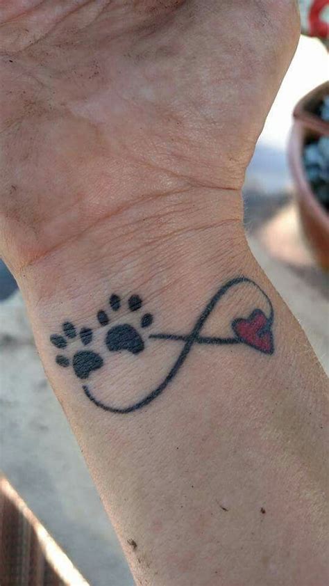 A Person With A Tattoo On Their Wrist Holding A Dogs Paw And Heart