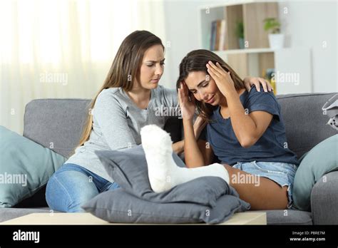 Sad Disabled Woman And Friend Comforting Her Sitting On A Couch In The