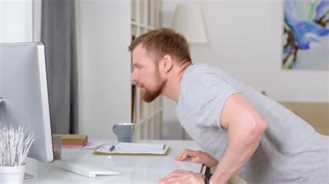 Man Doing Table Push Ups And Watching Workout Video On Computer Stock