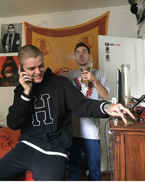 Two Men Standing In A Living Room Talking On Their Cell Phones While