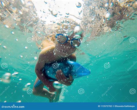 Un Ragazzo Del Bambino Sta Nuotando Underwater In Uno Stagno Sta Sorridendo E Trattenendo Il