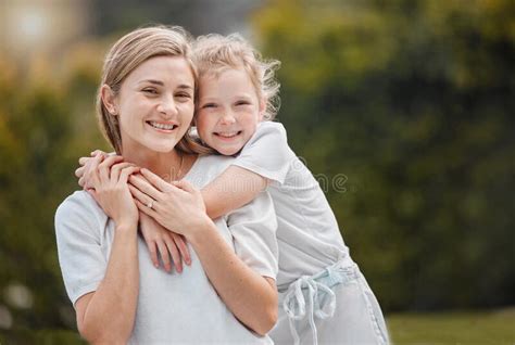 Portrait Of An Adorable Little Girl Hugging Her Mother From Behind
