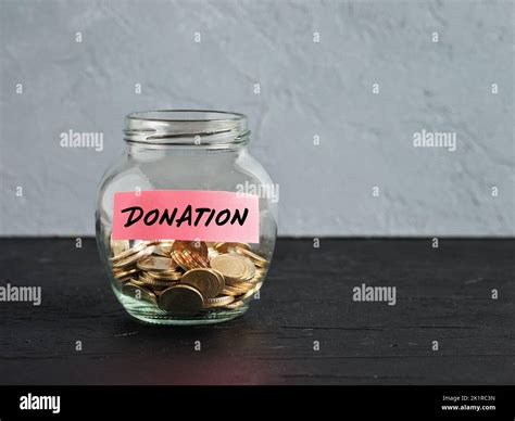Glass Jar With Coins And The Word Donation On A Label Charity Aid