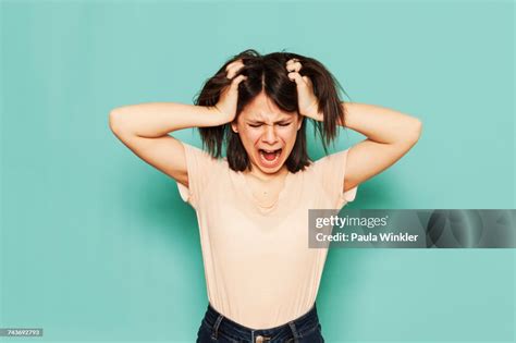 Irritated Girl Shouting With Hands In Hair Against Turquoise Background