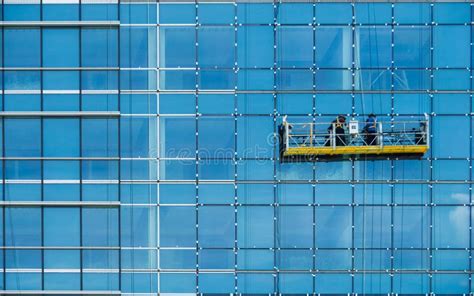 Worker Inspecting Glass Window Installation Of Tall Glass Exterior
