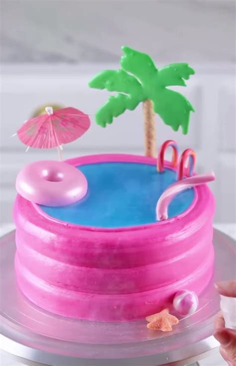 There Is A Cake That Looks Like A Pool With An Umbrella And Flamingos
