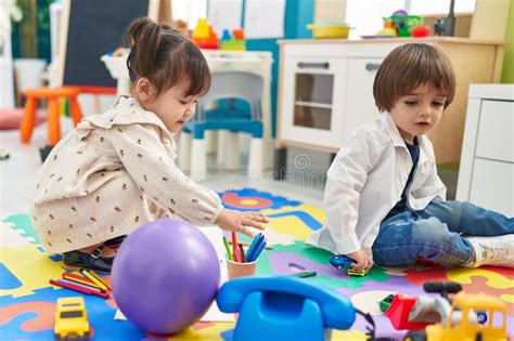 Two Kids Playing With Toys Sitting On Floor At Kindergarten Stock Photo