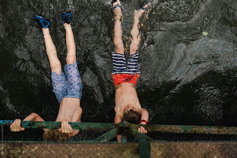 Two Boys Hanging On A Bridge With Their Legs In The Current Of A River