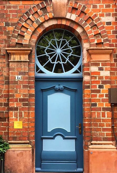 A Blue Front Door With An Arched Window On The Side Of A Red Brick Building