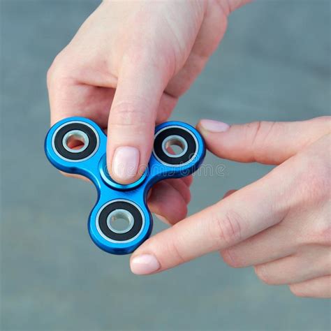 Girl Playing Blue Metal Spinner In Hands On The Street Female Hands Holding Popular Fidget