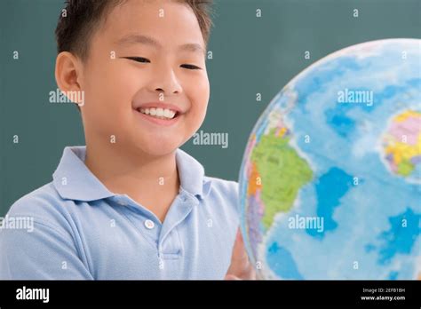 Close Up Of A Schoolboy Looking At A Globe In A Classroom Stock Photo
