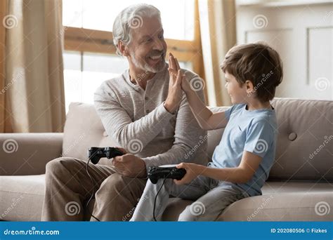 Overjoyed Grandfather And Grandson Giving High Five Playing Video Game