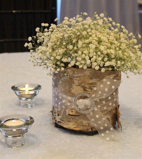 A Vase Filled With White Flowers Sitting On Top Of A Table Next To Two
