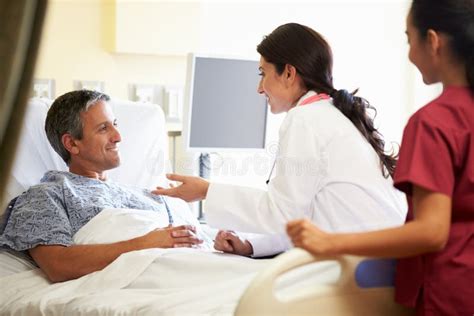 Female Doctor Talking To Male Patient In Hospital Room Stock Image