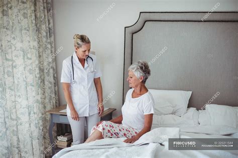 Female Doctor Interacting With Senior Patient At Home — Care Abode