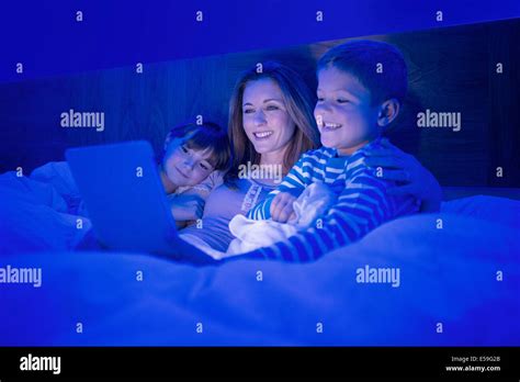 Mother And Children Using Digital Tablet In Bed Stock Photo Alamy