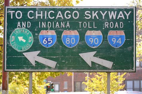 A Green And White Street Sign With Arrows Pointing To Chicago Skyway