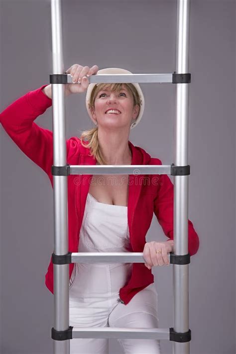 Woman Wearing A Hard Hat And Holding A Telescopic Ladder Stock Photo